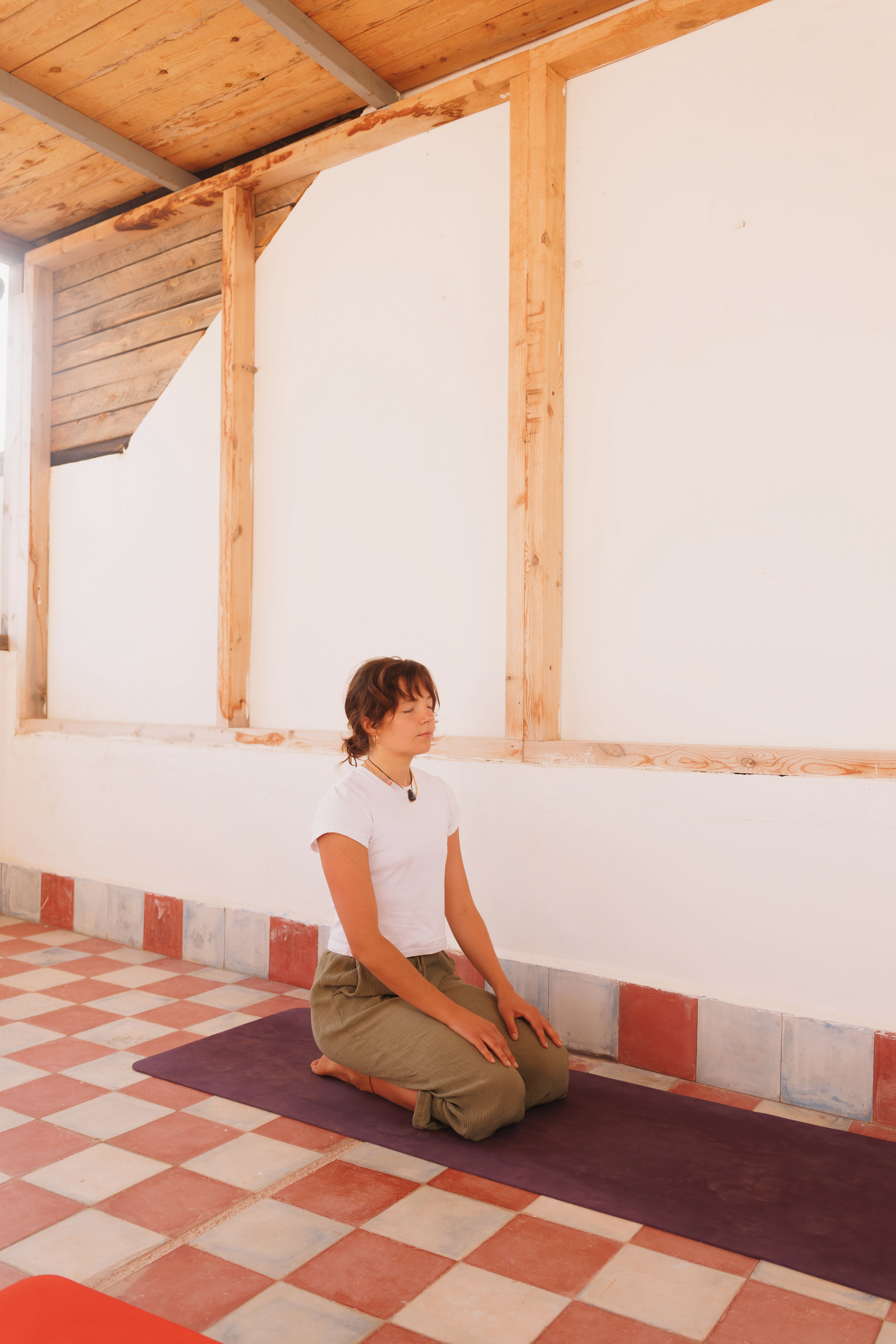 Clarisse assise sur son tapis de yoga dans un studio lumineux