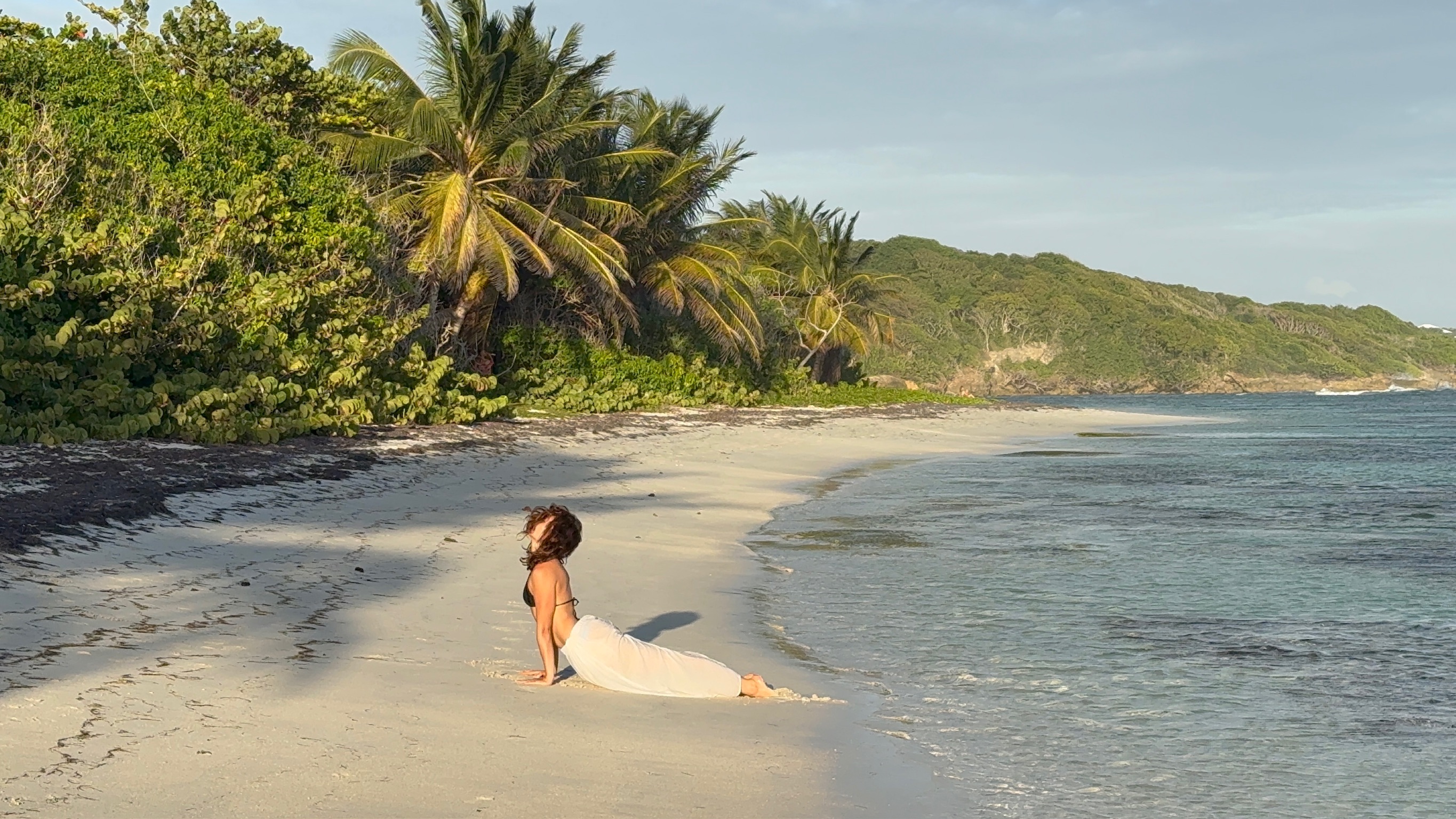Clarisse pratiquant le yoga sur le sable au bord de l’océan